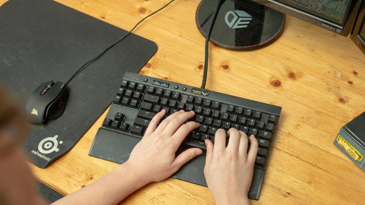 Student typing on a keyboard; code is displayed the computer screen. 